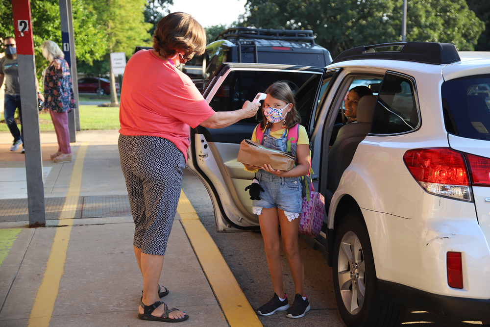 Picture of FPS employee taking the temperature of a FPS student getting out of her car for school.