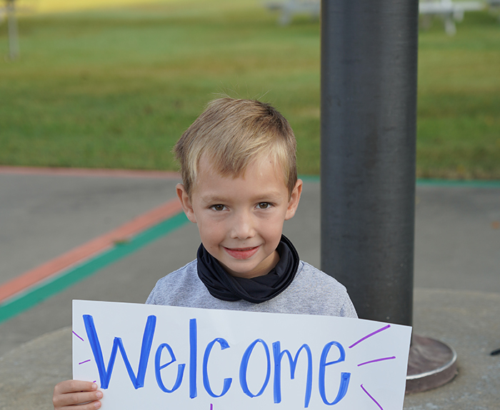 Student holds sign Welcome to Holcomb, welcoming new students back to the first day of school!