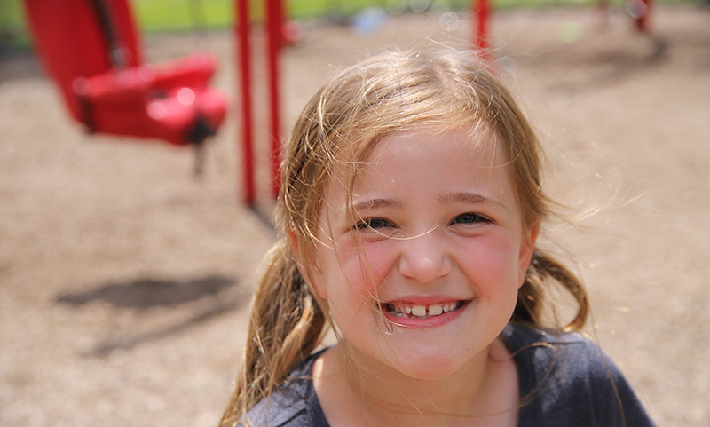 Vandergriff student plays on the playground and smiles for the camera.