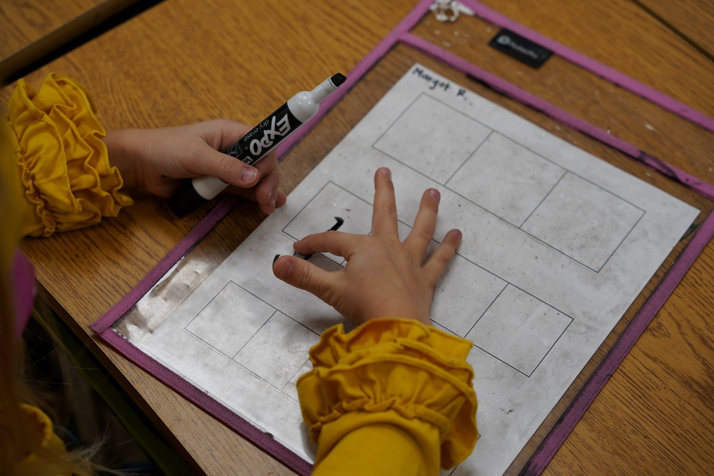 students hands working on an assignment with expo marker
